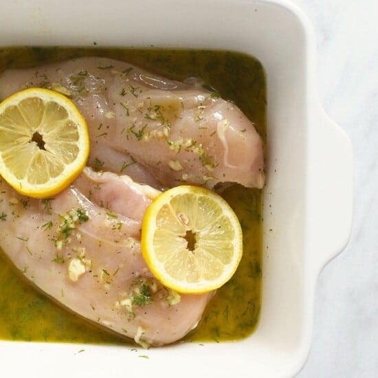 Lemon-marinated chicken breasts showcased in a white dish.