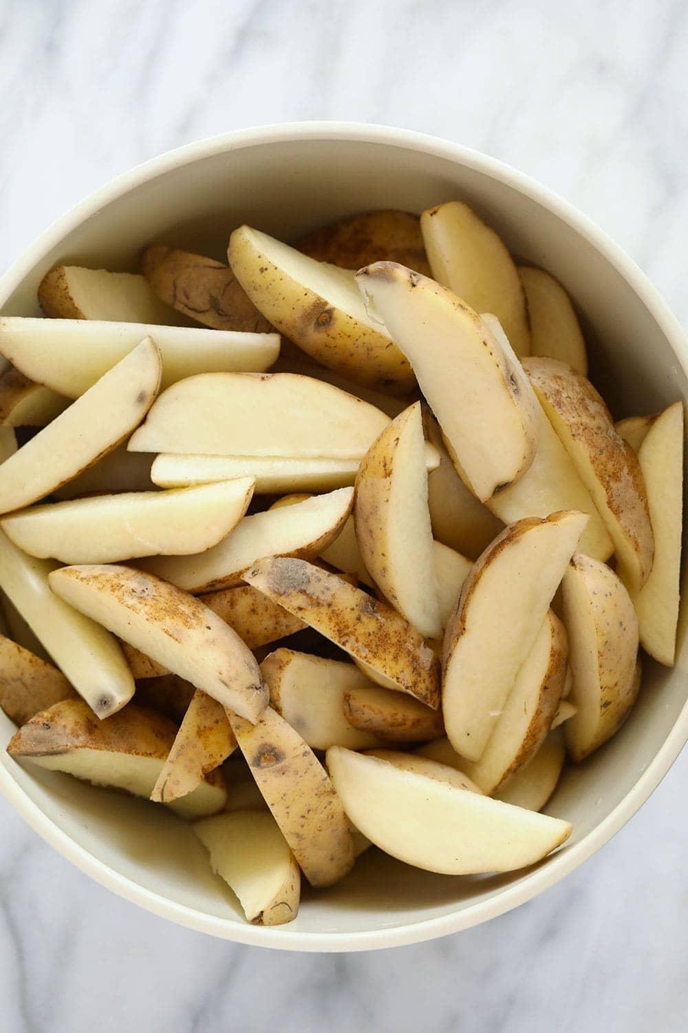 Chopped potato wedges in a bowl. 