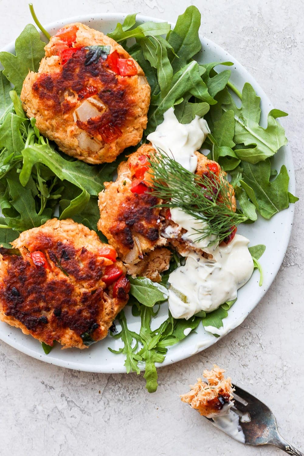 salmon patties on a plate atop arugula