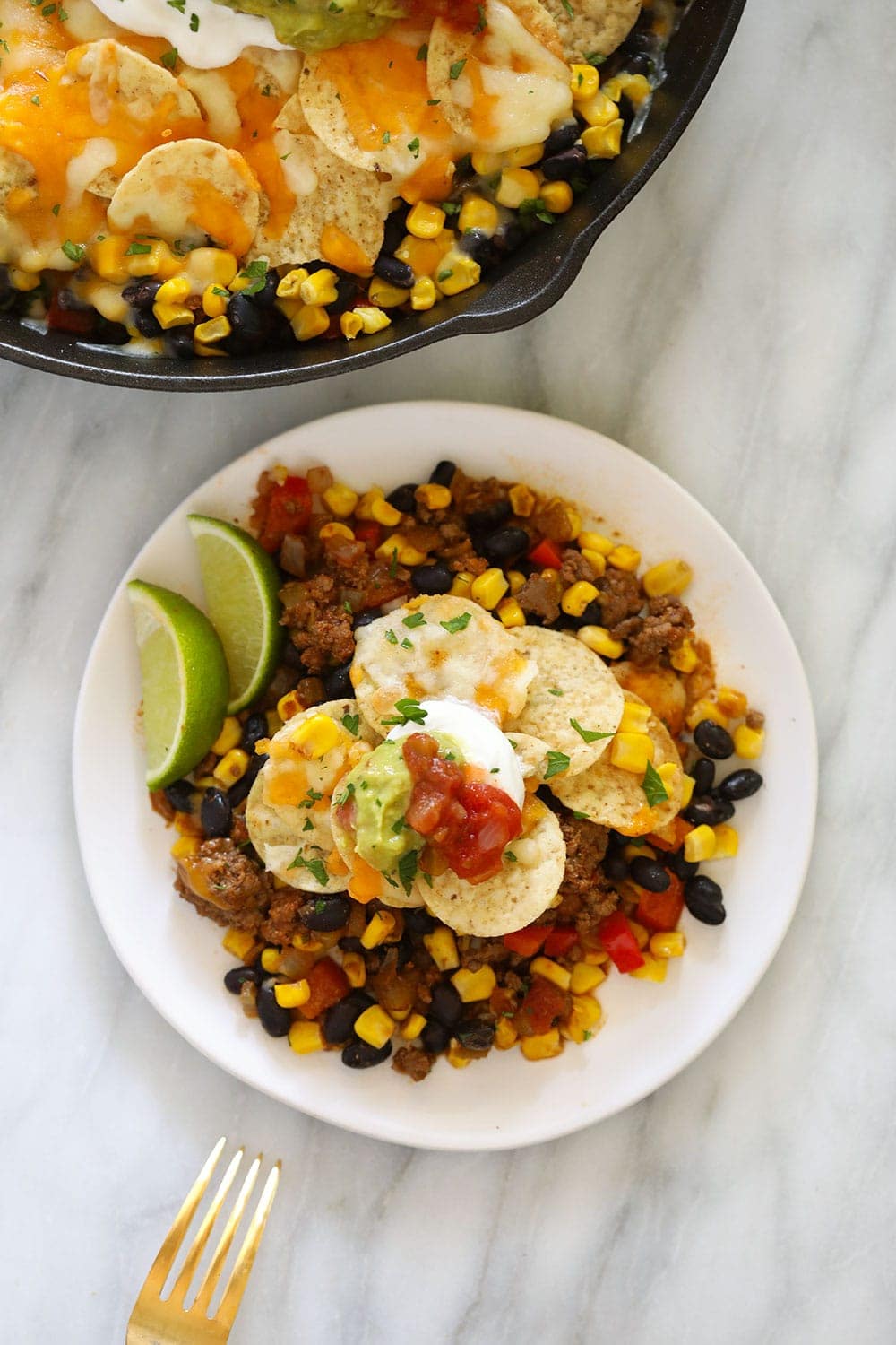 easy taco casserole on a plate topped with greek yogurt and guacamole