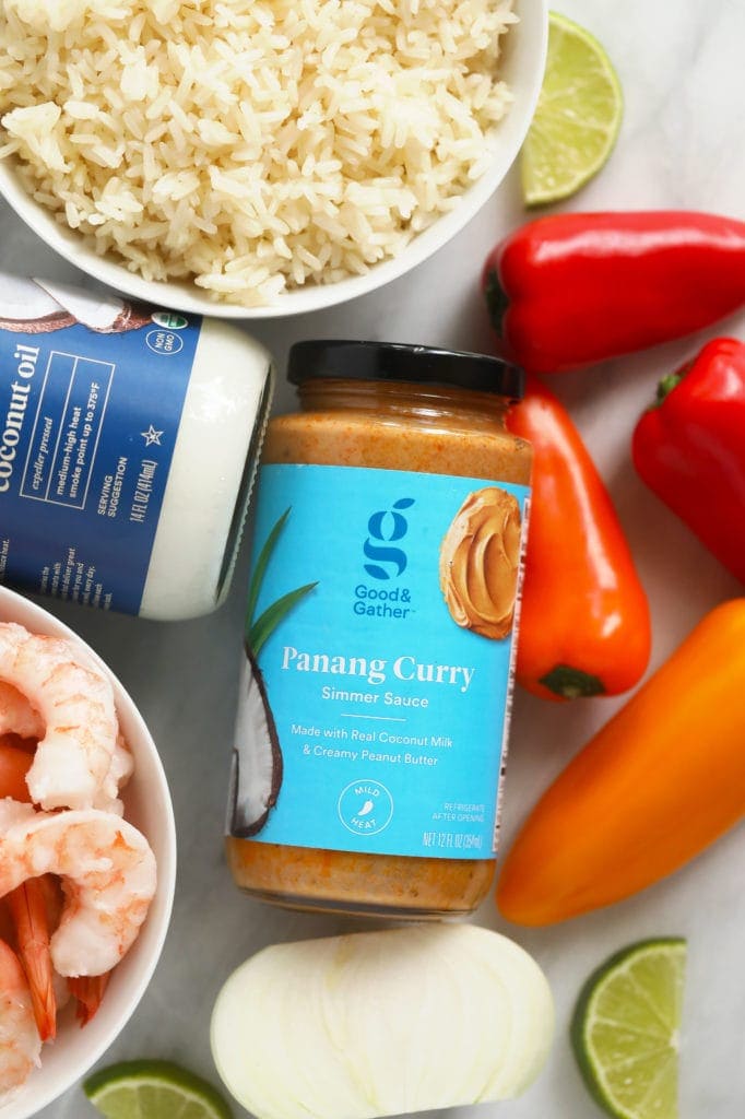 Panang curry simmer sauce, coconut oil, peppers, and shrimp laying on a cutting board.