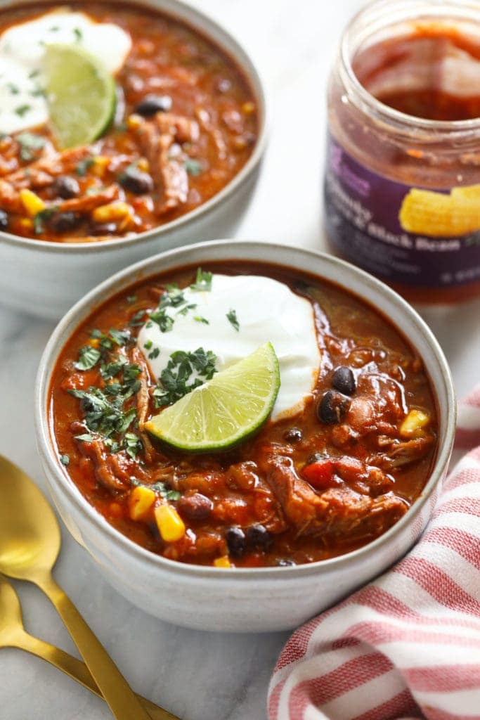 pork chili in bowl with Greek yogurt and a lime wedge.