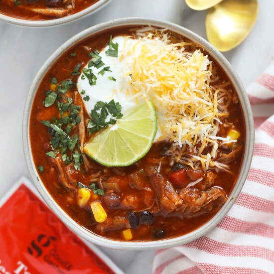 two bowls of pork chili with cheese and sour cream.