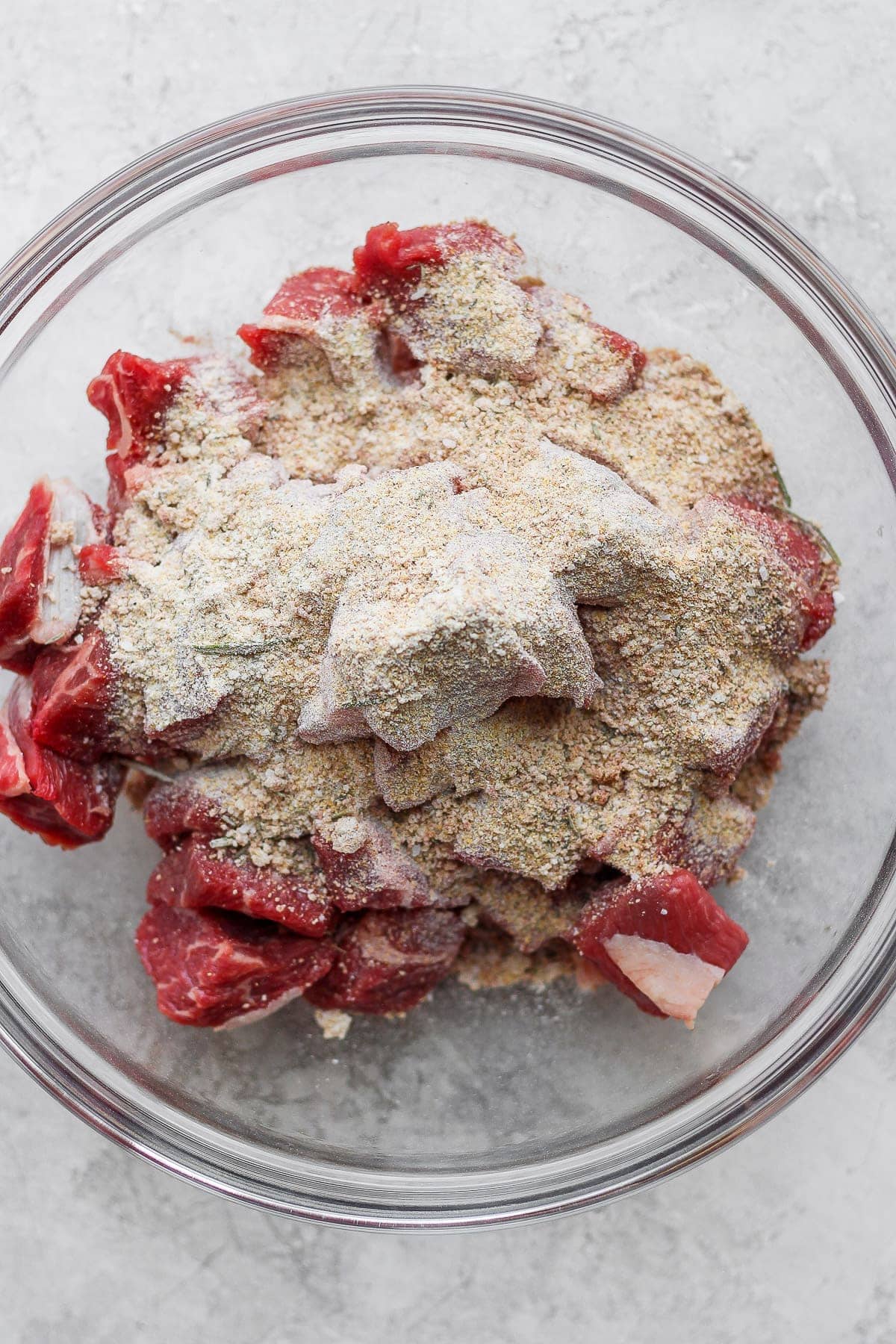 Beef chunks and beef stew seasoning in a bowl. 