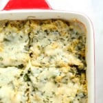 cheesy spinach casserole in a red and white dish.