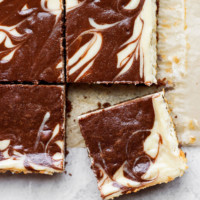 a slice of chocolate swirl cheesecake bars on top of a piece of paper.