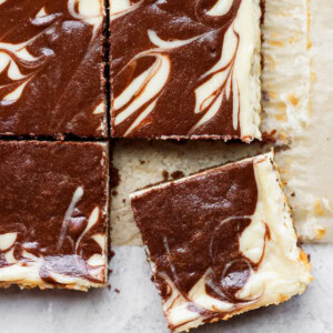 a slice of chocolate swirl cheesecake bars on top of a piece of paper.