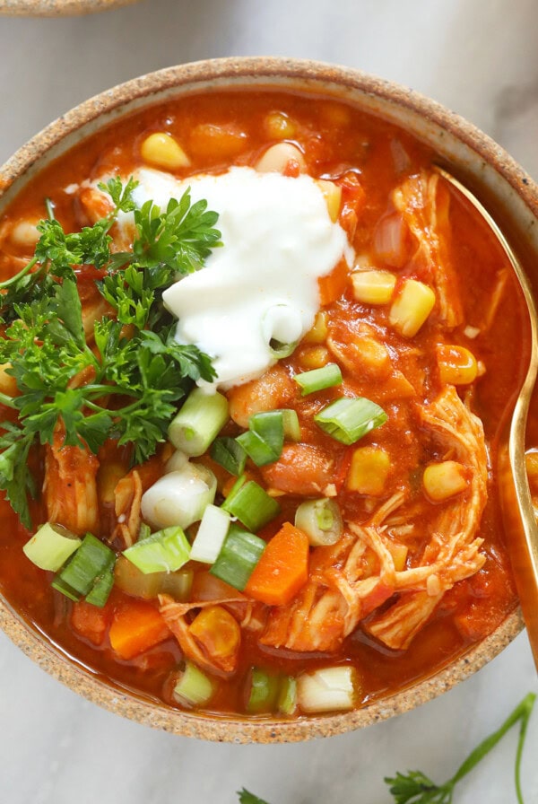 a bowl of buffalo chicken chili with sour cream and carrots.