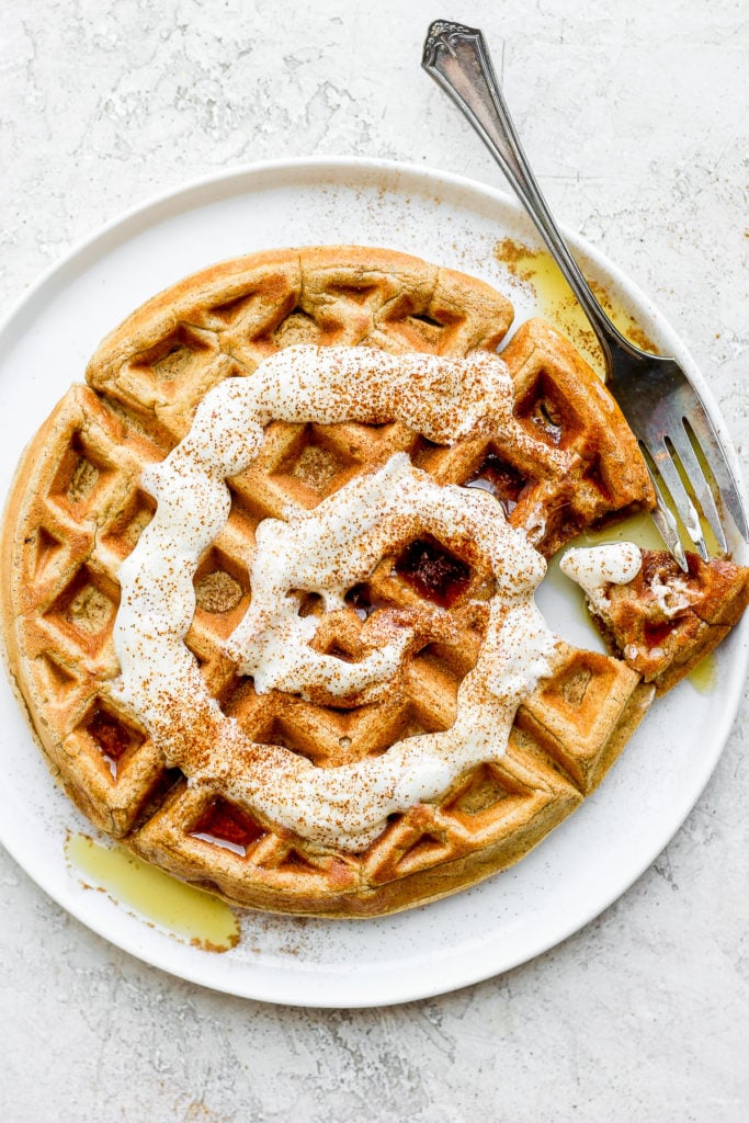 cinnamon roll waffles topped with a greek yogurt cream cheese drizzle