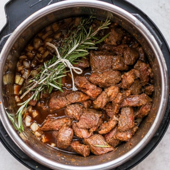 Instant pot beef stew infused with aromatic rosemary sprigs.