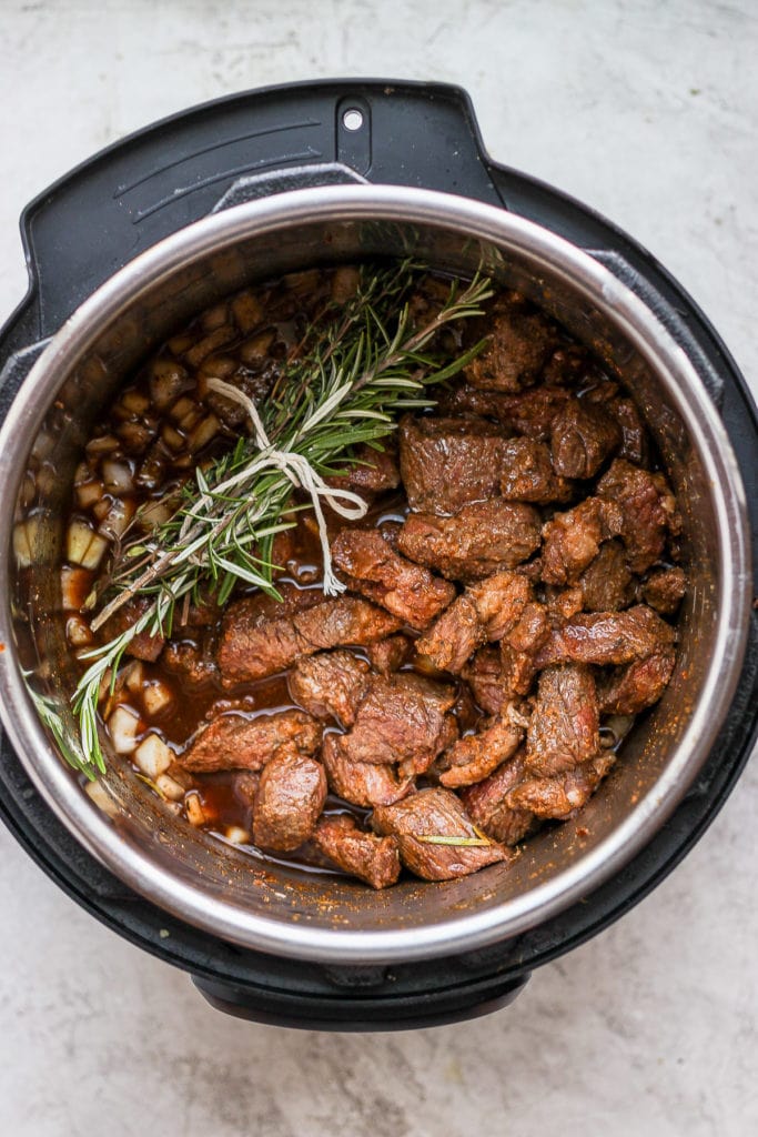 beef stew in the instant pot with an herb bundle placed on top