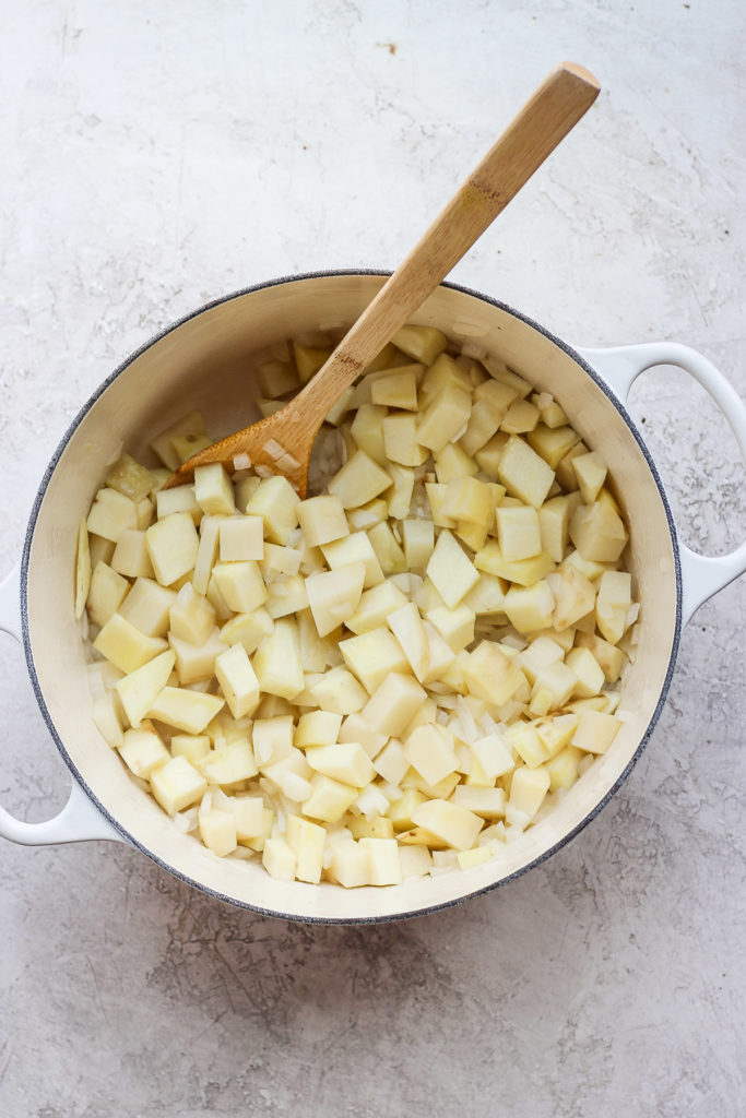 Potatoes, onions, and garlic cooking in a dutch oven. 