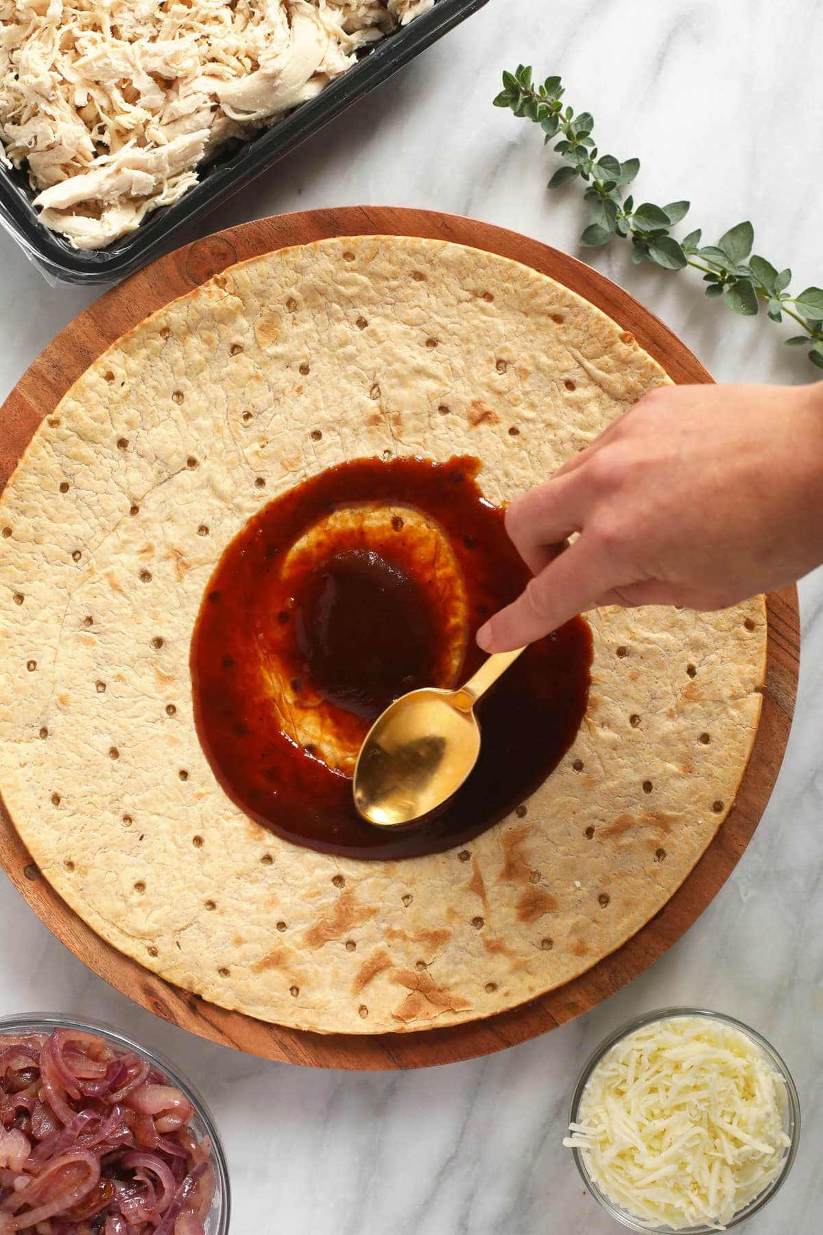 spreading bbq sauce on pizza crust