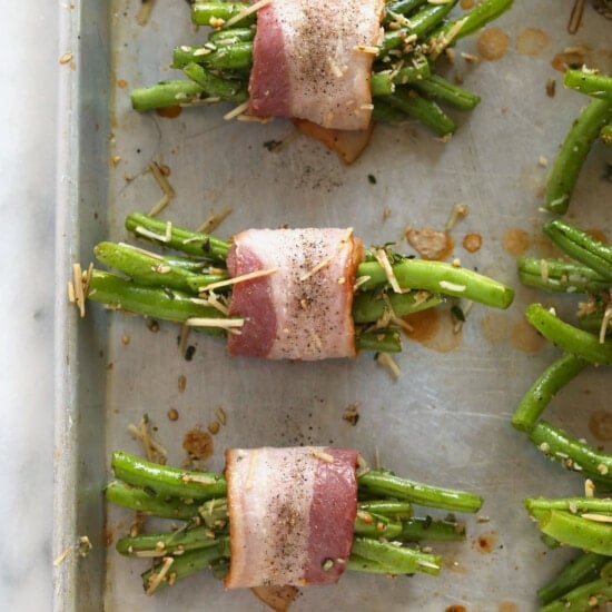Bacon-wrapped green beans baked on a sheet.