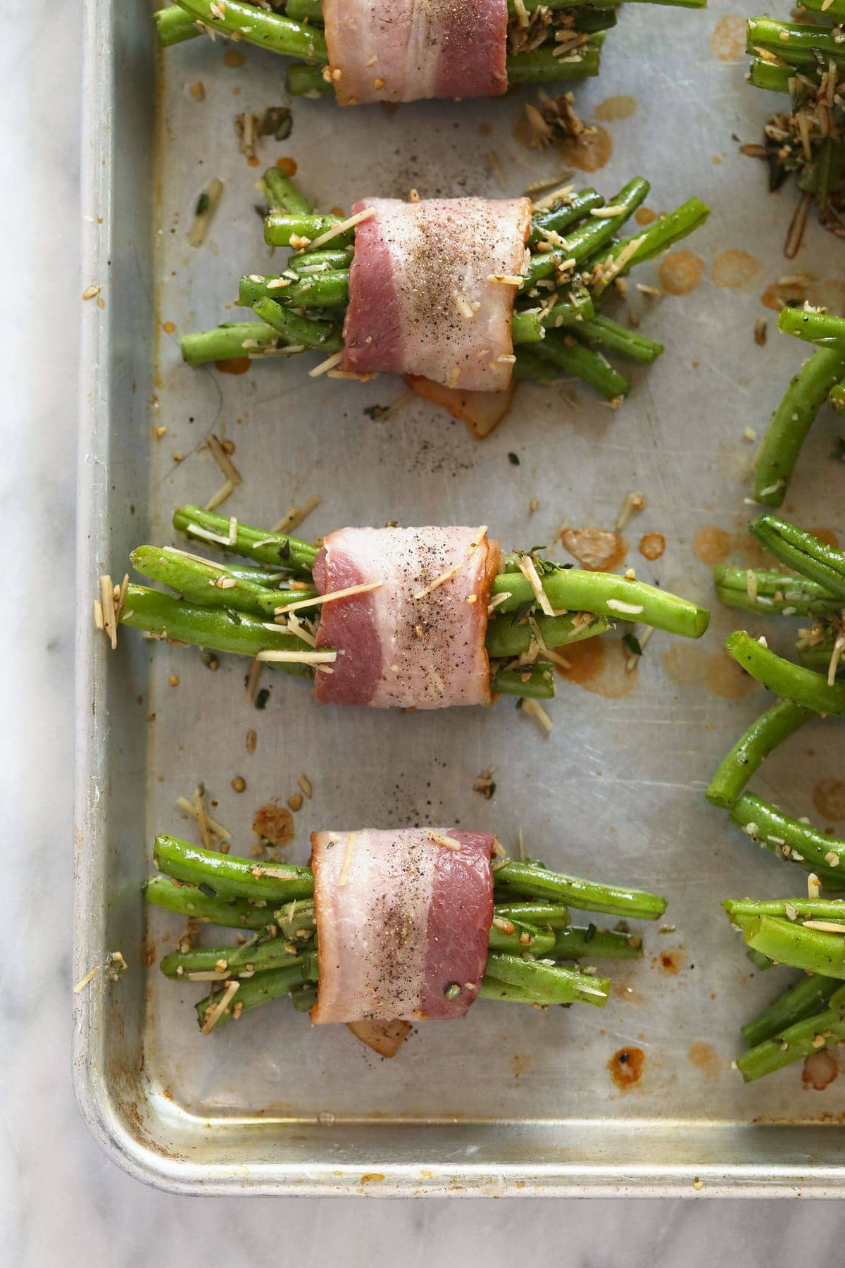 bacon wrapped green beans ready to be baked on a baking sheet