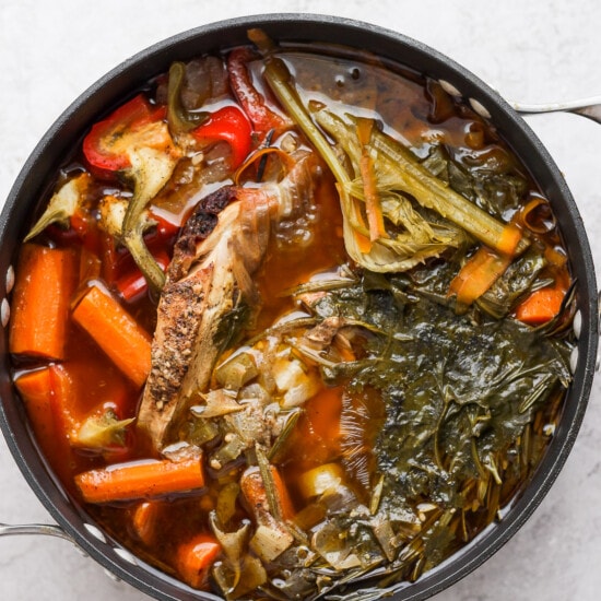 chicken stew with vegetables in a pan on a white background.