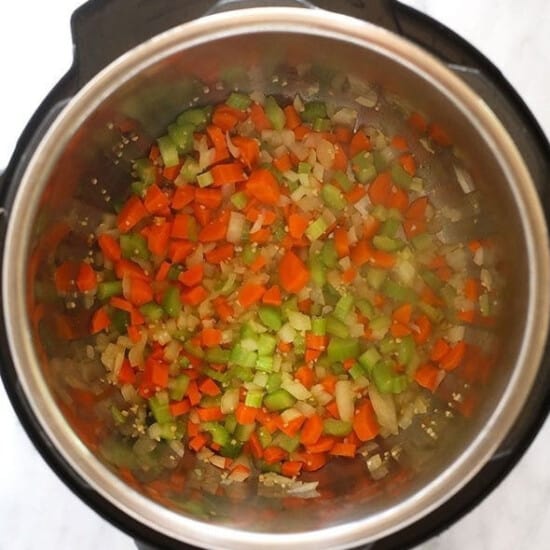 An instant pot filled with chopped veggies.