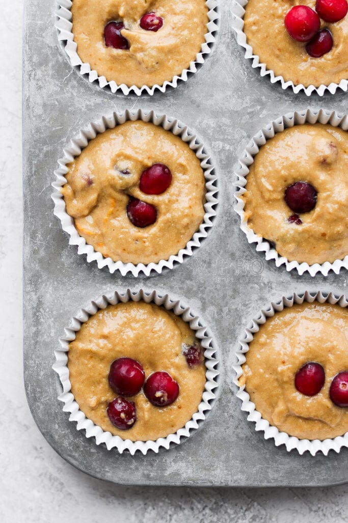 cranberry orange muffins in a muffin tin, ready to be baked
