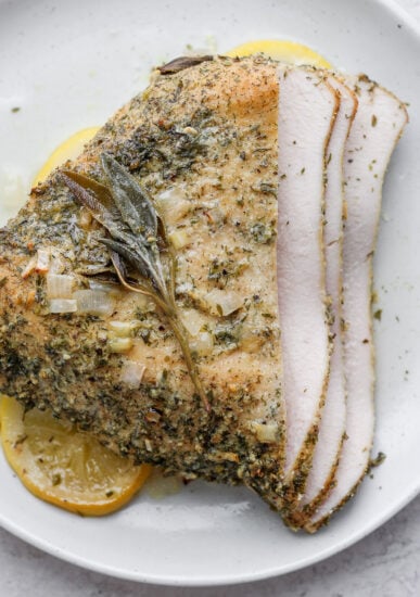 Turkey breast recipe: roasted turkey with herbs on a white plate.