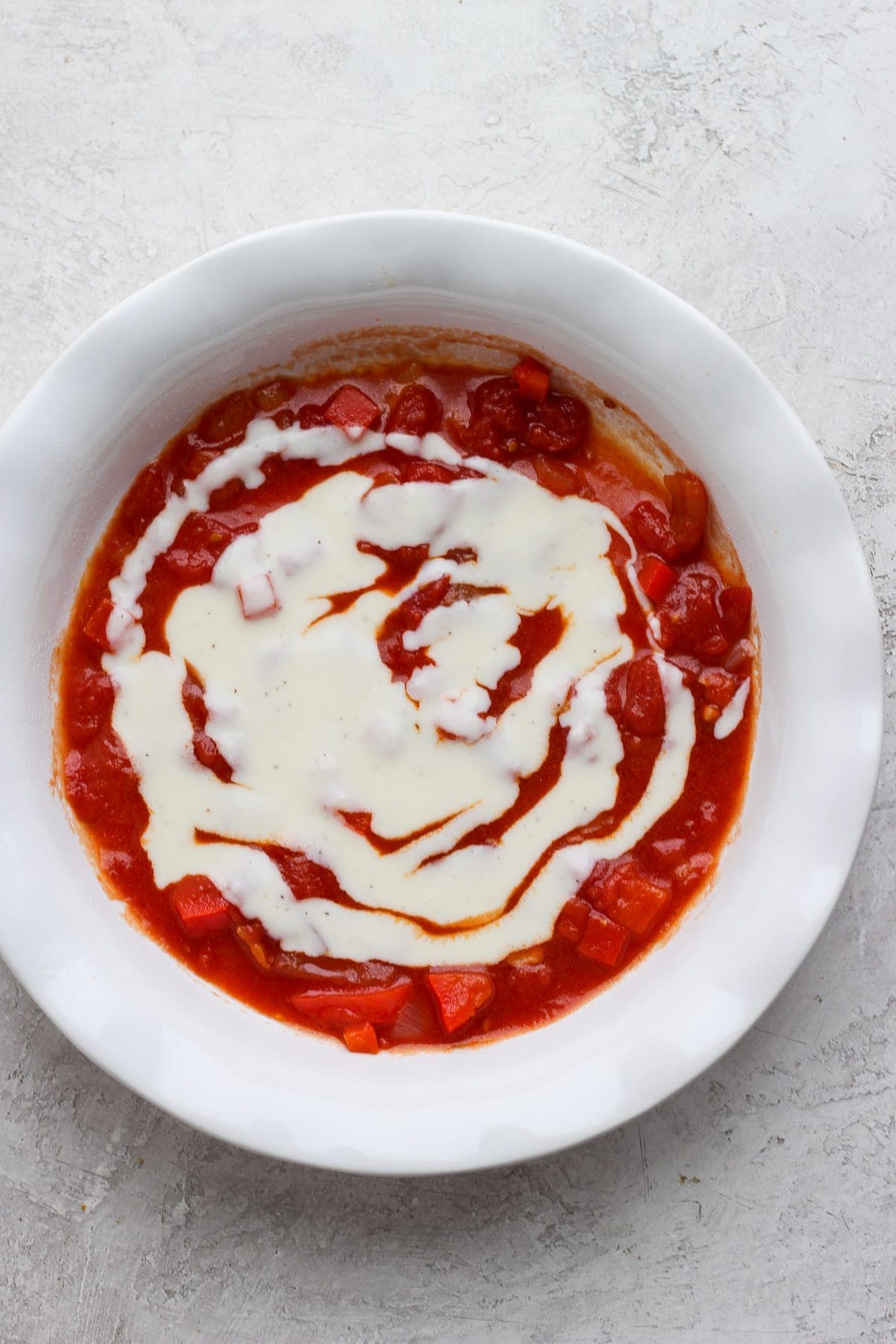 Red and white sauce in the bottom of a baking dish. 