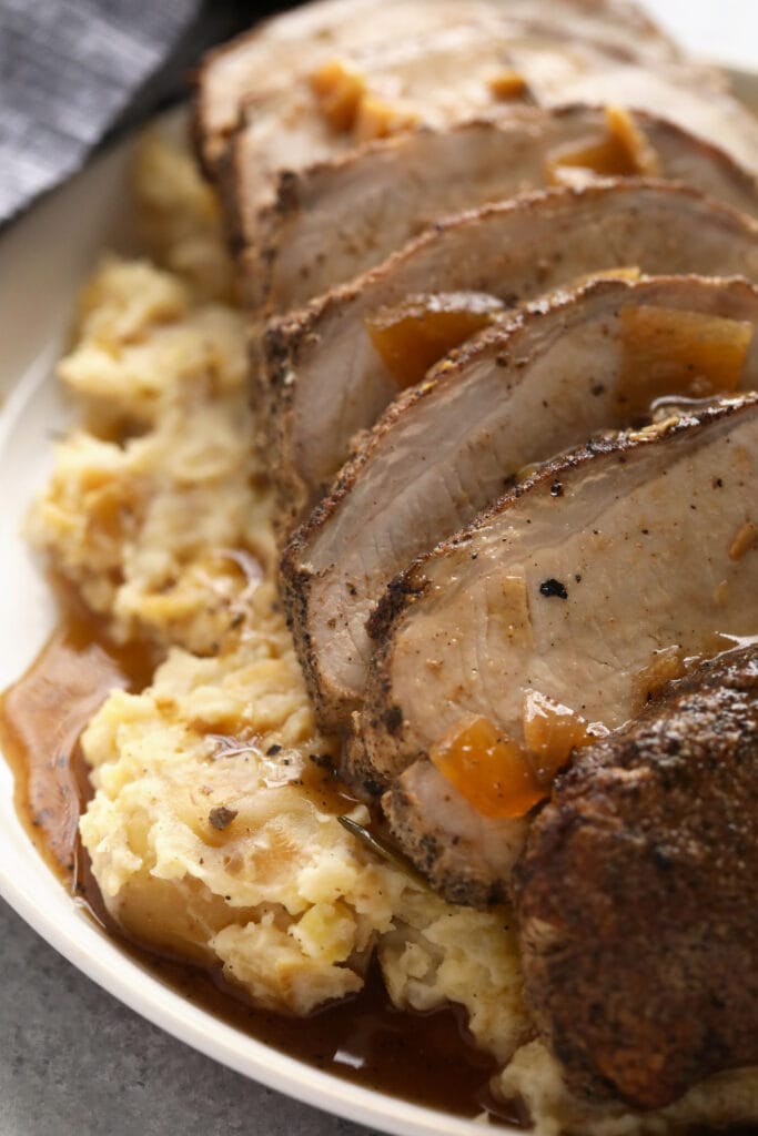 slow cooker pork ، sliced and looking delicious covered in gravy.