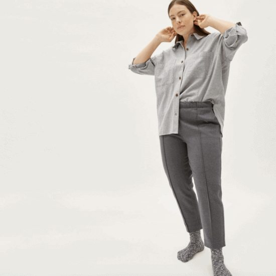 a woman wearing a grey shirt and grey trousers.