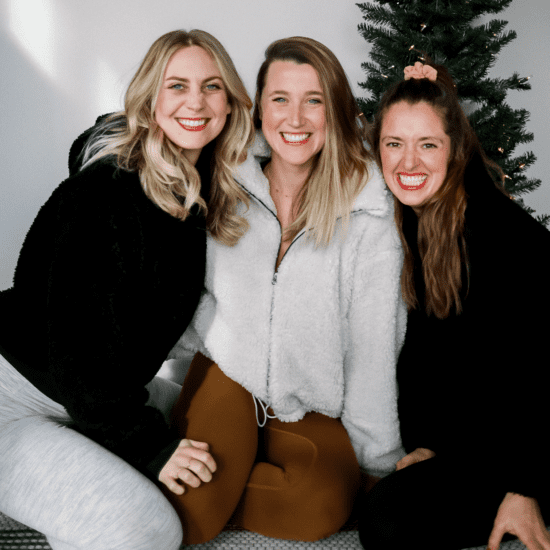 Three women posing in front of a Christmas tree, showcasing their festive Lululemon holiday wish list.