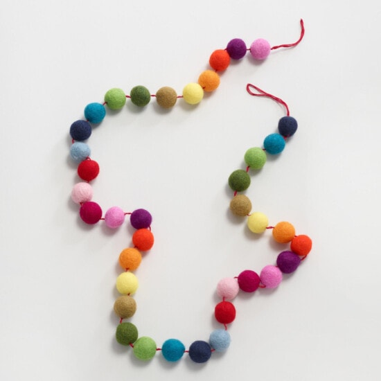 a colorful felt ball garland on a white surface.