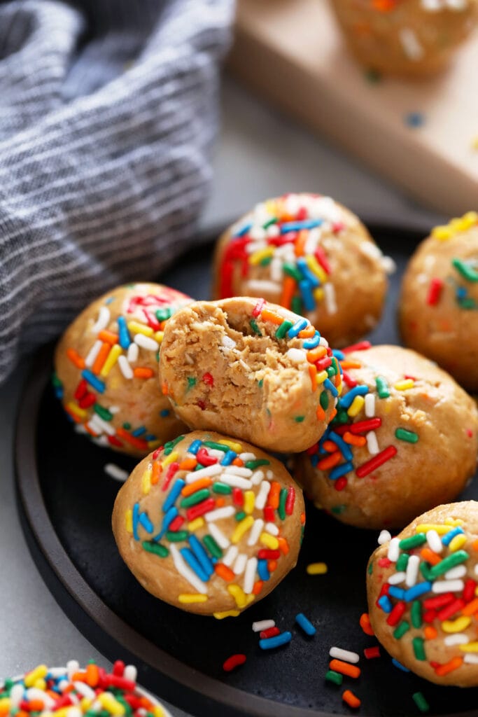 cake batter protein balls with a bite taken out of them 