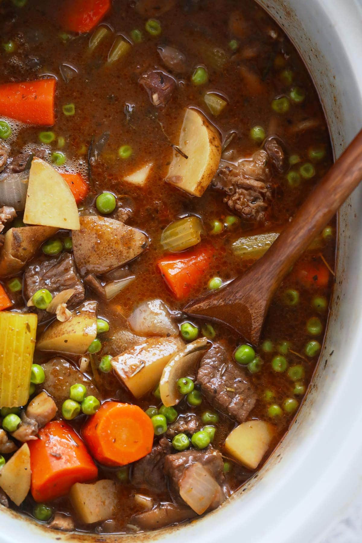 beef stew in the slow cooker being stirred with a spoon