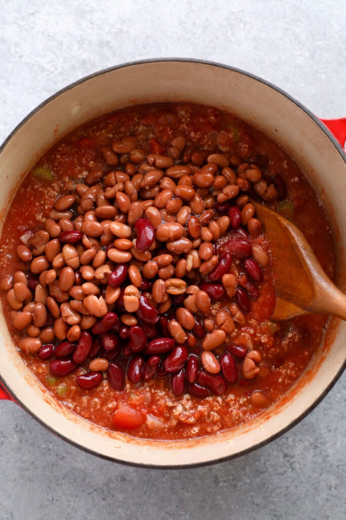 Beans being added to a dutch oven to make turkey chili.