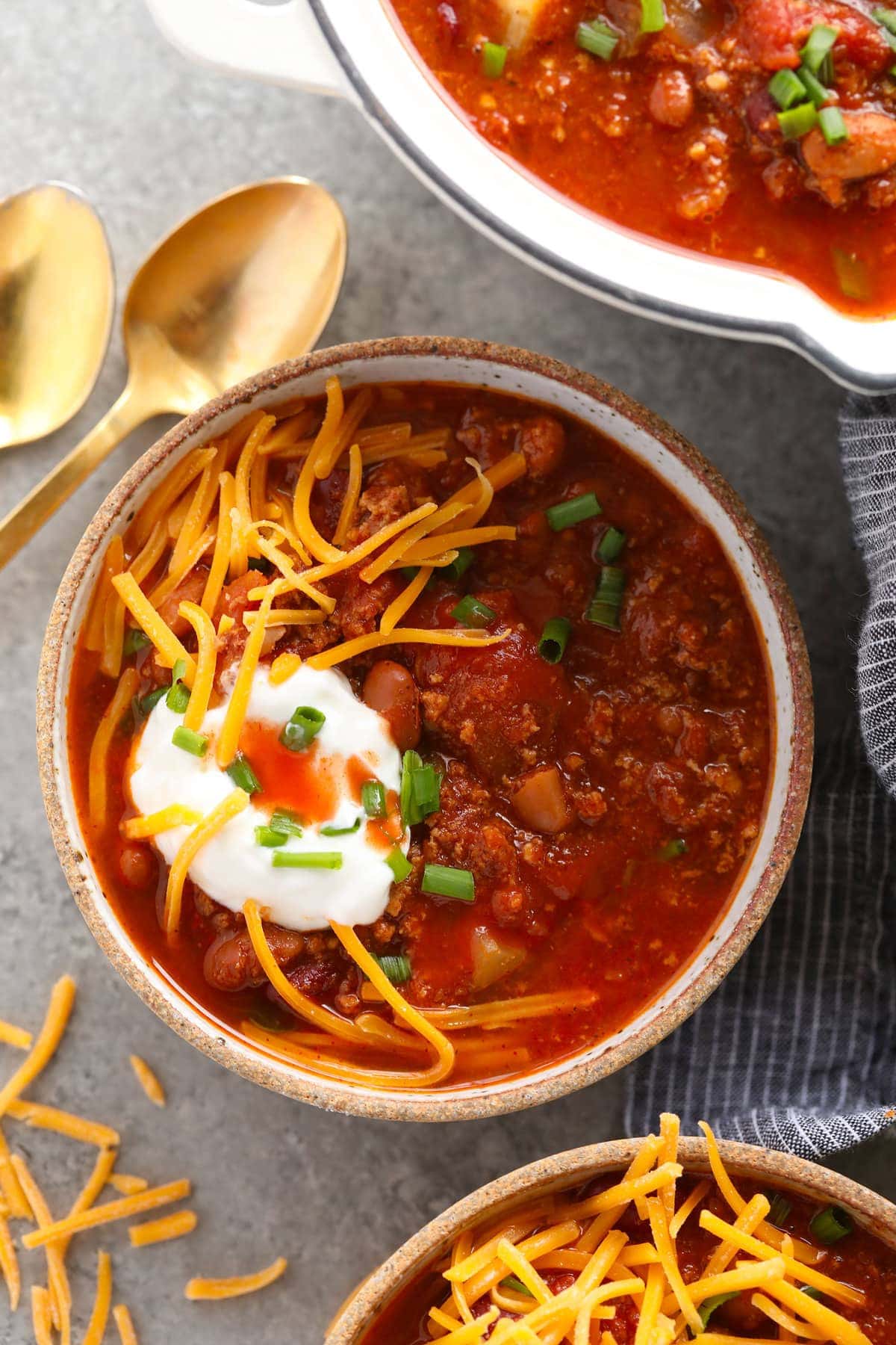 Turkey chili topped with sour cream and shredded cheese in a bowl.