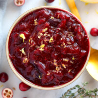 Unique cranberry sauce recipe served in a bowl with lemon and thyme.