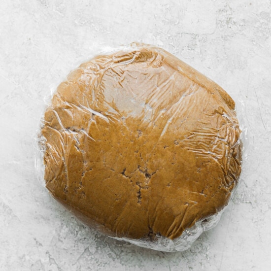 a piece of dough wrapped in plastic on a white surface.