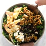 A Thanksgiving salad featuring a bowl of kale with apples and walnuts.