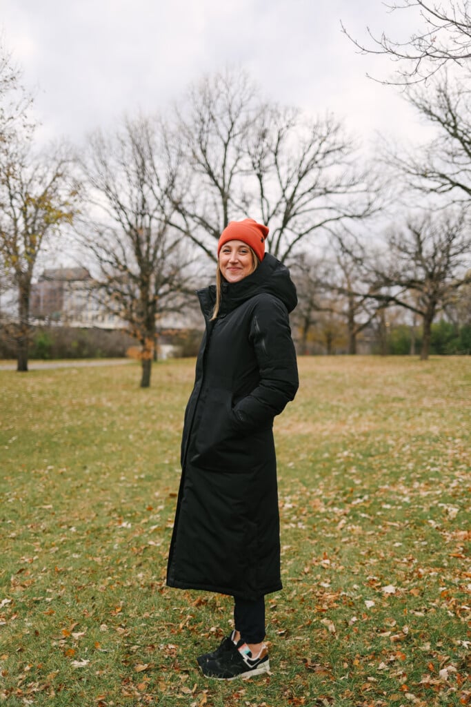 Woman wearing a long jacket and smiling at the camera.