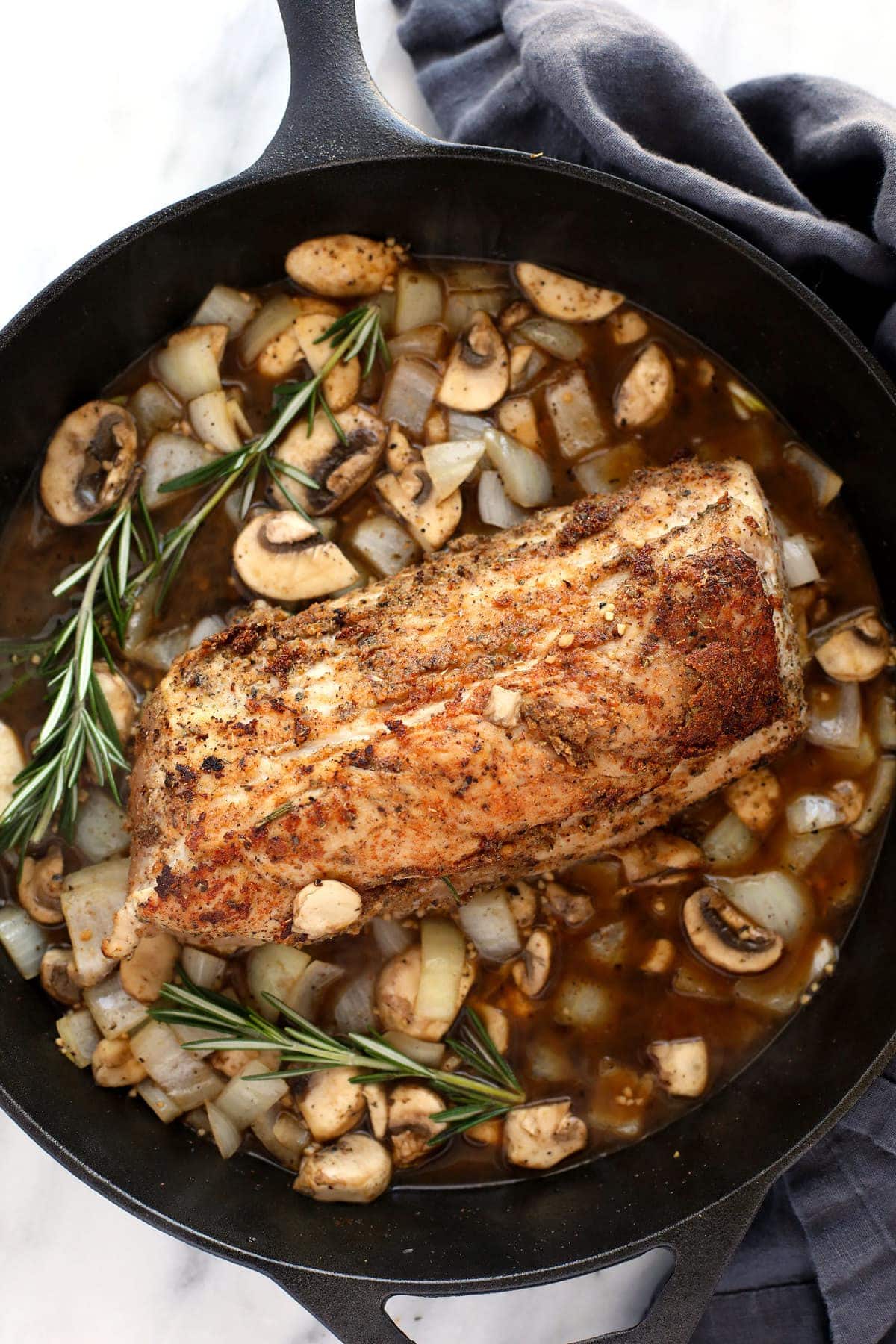 pork tenderloin in gravy on cast iron pan.