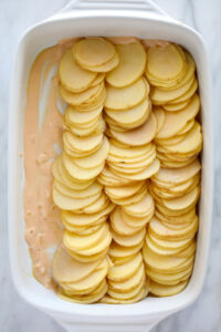 Cheesy scalloped potatoes baked in a white dish.