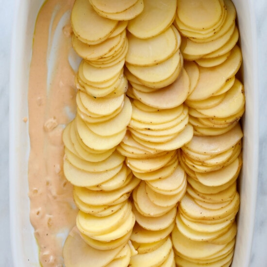Cheesy scalloped potatoes baked in a white dish.