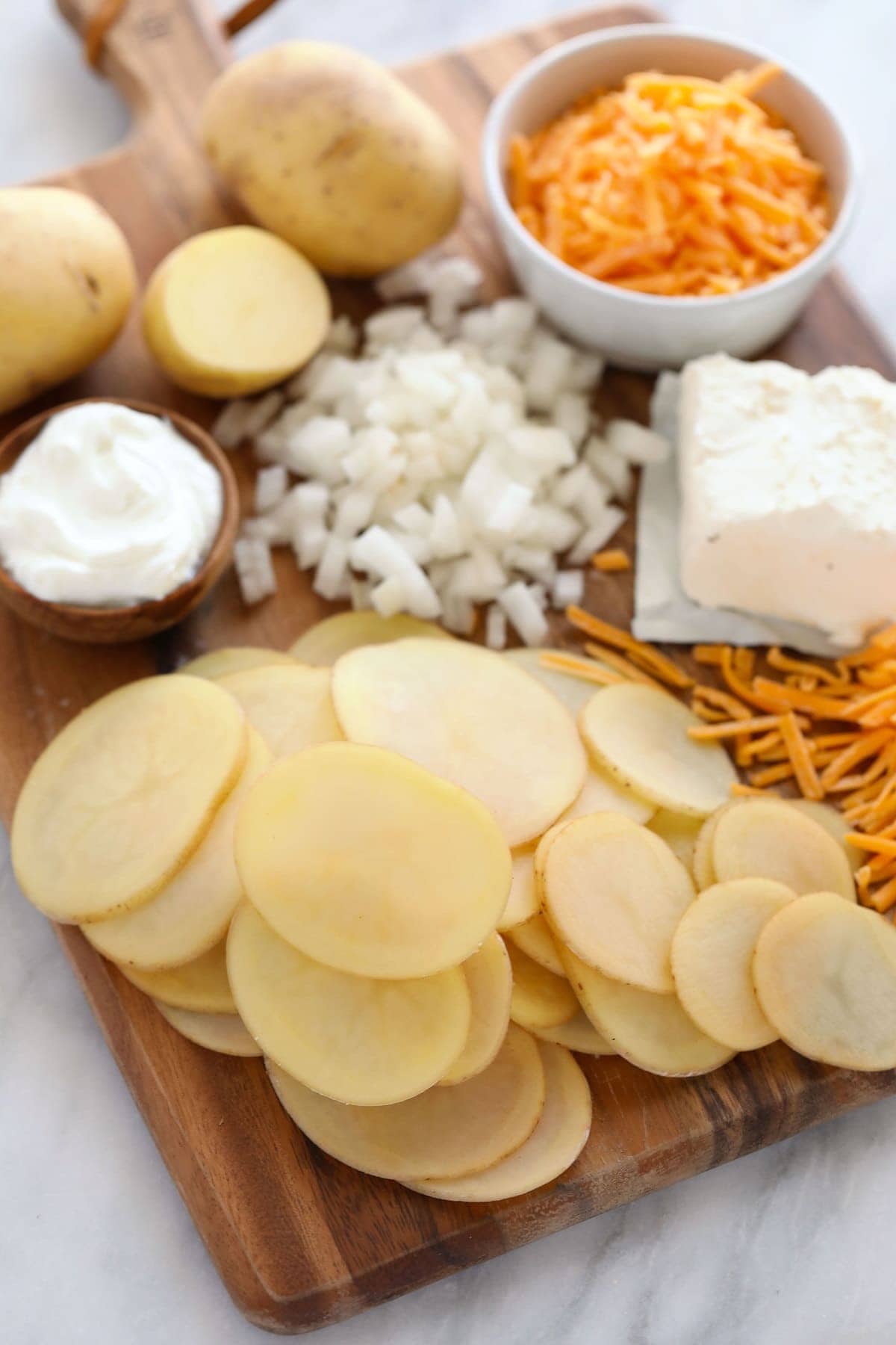 all the ingredients for scalloped potatoes on a cutting board.