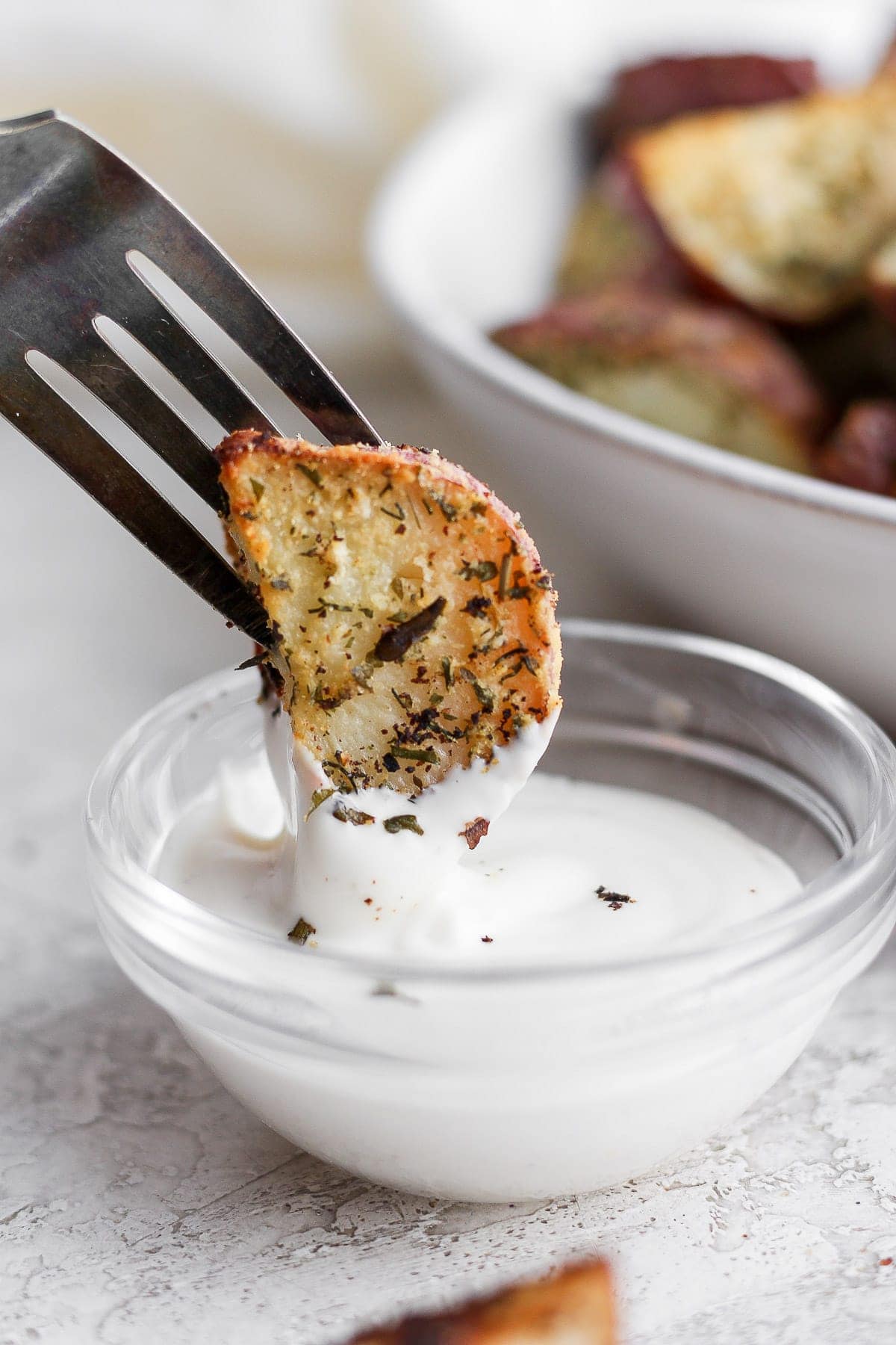 roasted red potato being dipped into ranch dressing