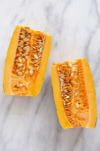 Two roasted delicata squash slices on a marble table.