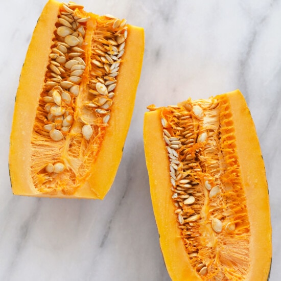 Two roasted delicata squash slices on a marble table.