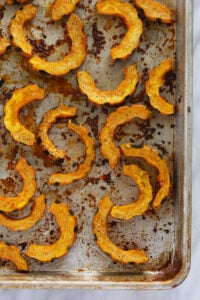 Delicata squash roasted on a baking sheet.