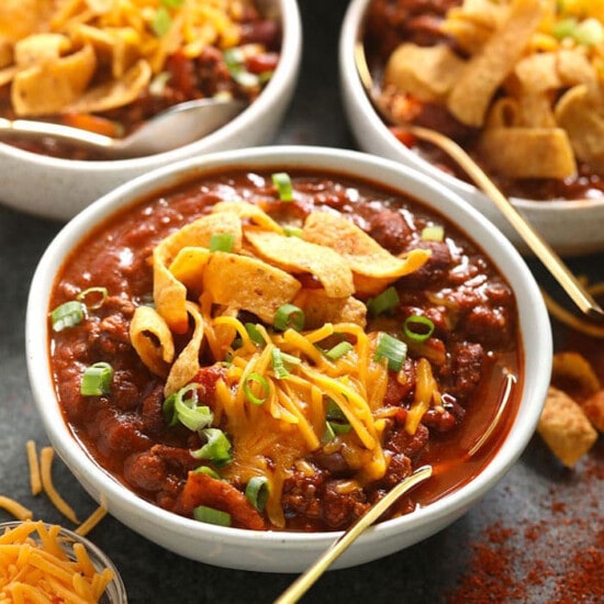 four bowls of chili with cheese and tortilla chips.