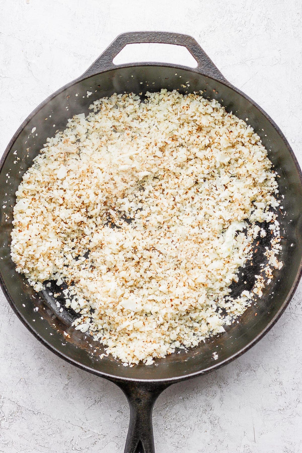 riced cauliflower in a skillet being browned