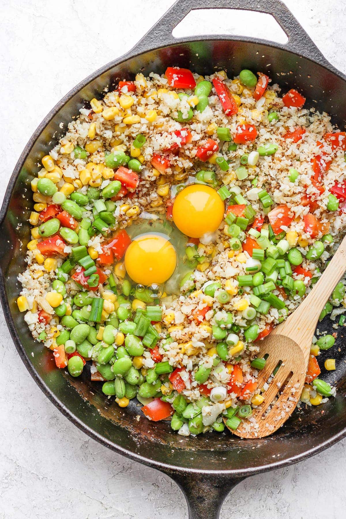 cauliflower fried rice with 2 eggs cracked in the middle of the skillet