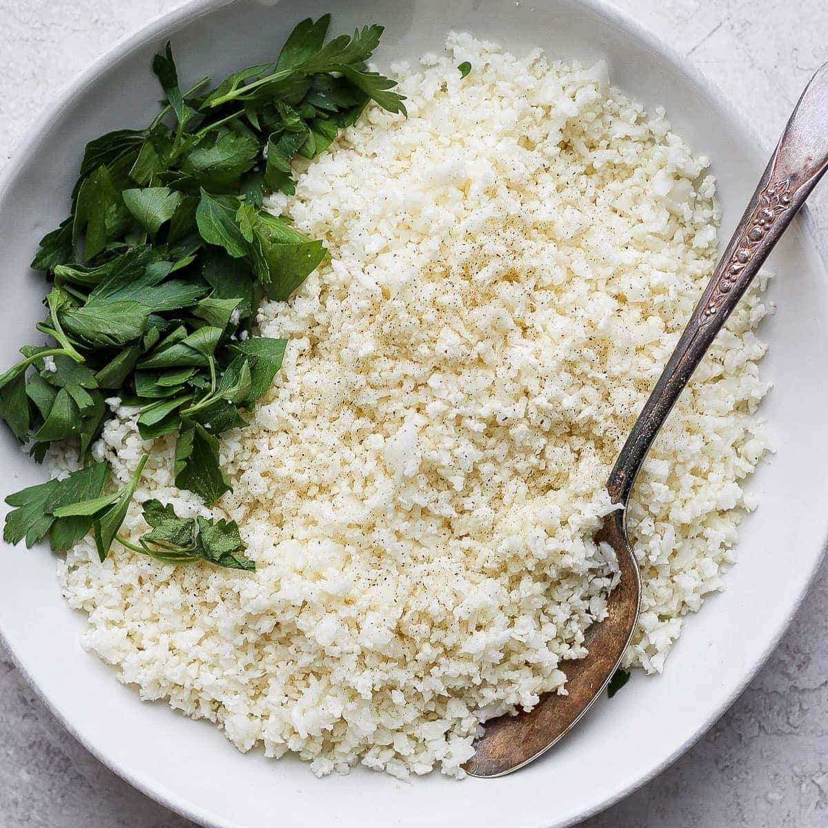 a bowl of white rice with parsley and a spoon.