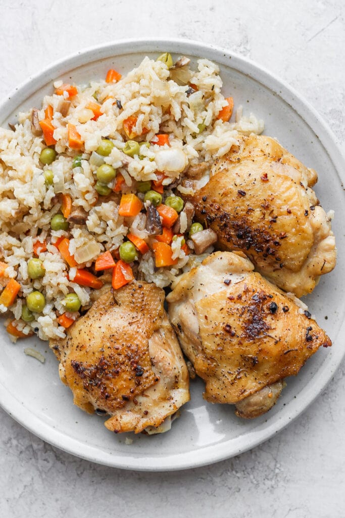 seared chicken thighs and rice on plate.