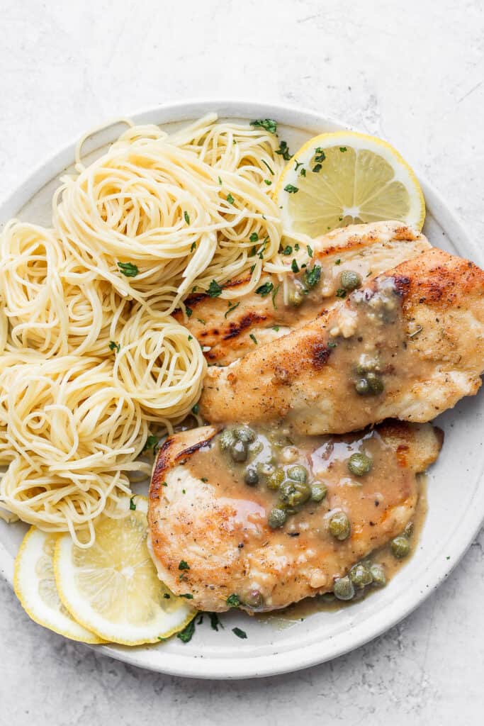 Chicken piccata on a plate with angel hair pasta. 